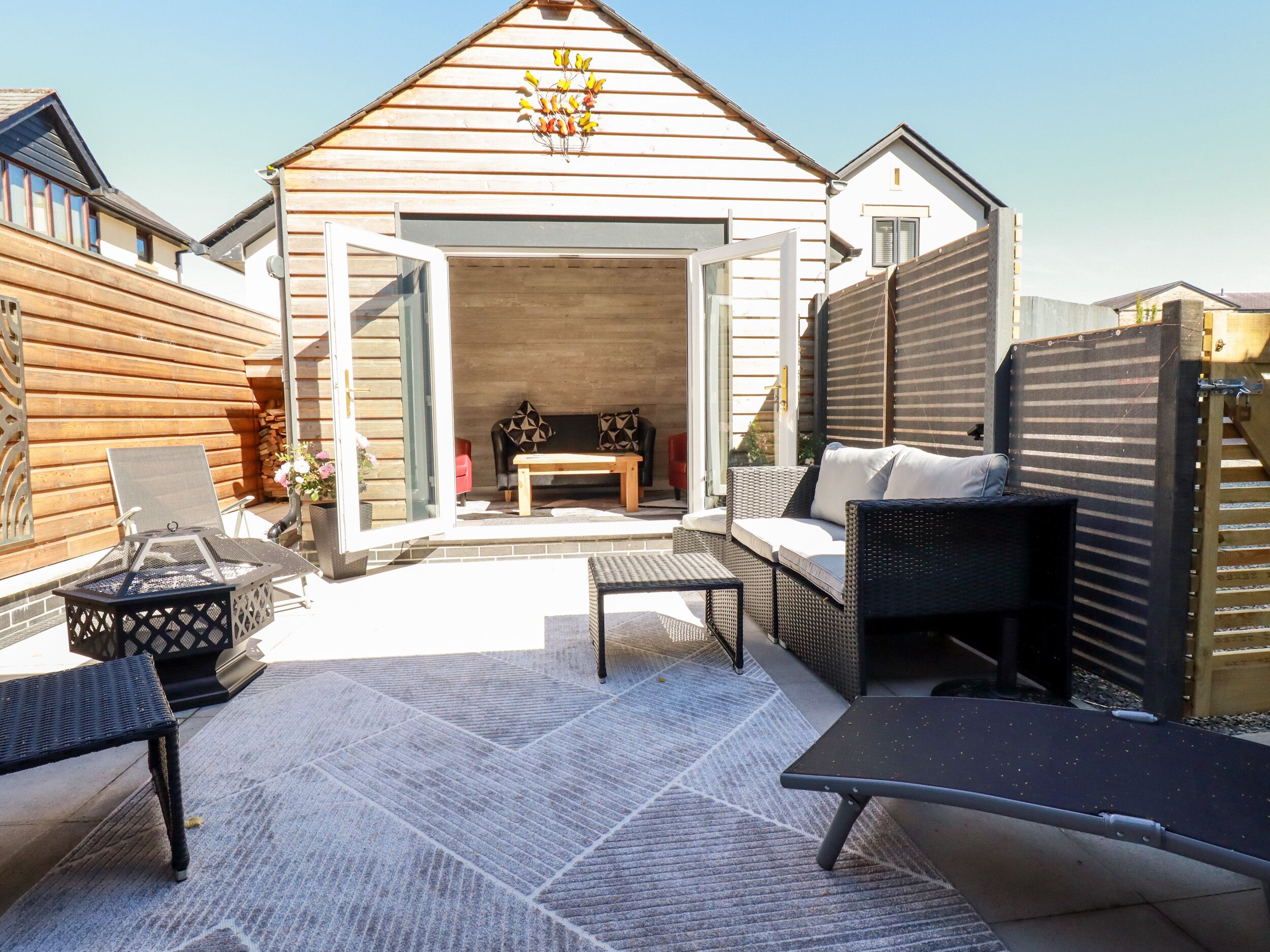 A cozy outdoor patio area with a wooden deck, a seating area with a sofa and chairs, and a small table.