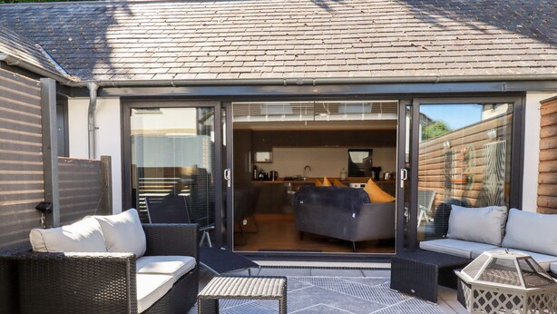 Un espacio exterior moderno con sofá, sillas y una mesa.