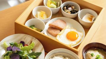 Bandeja de comida con diversos platos, incluyendo arroz, ensalada, un huevo y varios recipientes pequeños con guarniciones.