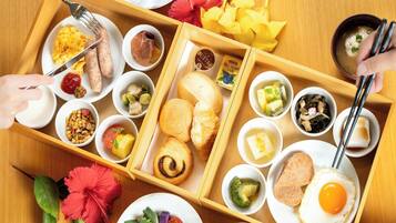 A wooden tray with various breakfast items including scrambled eggs, sausages, toast, and a variety of side dishes.