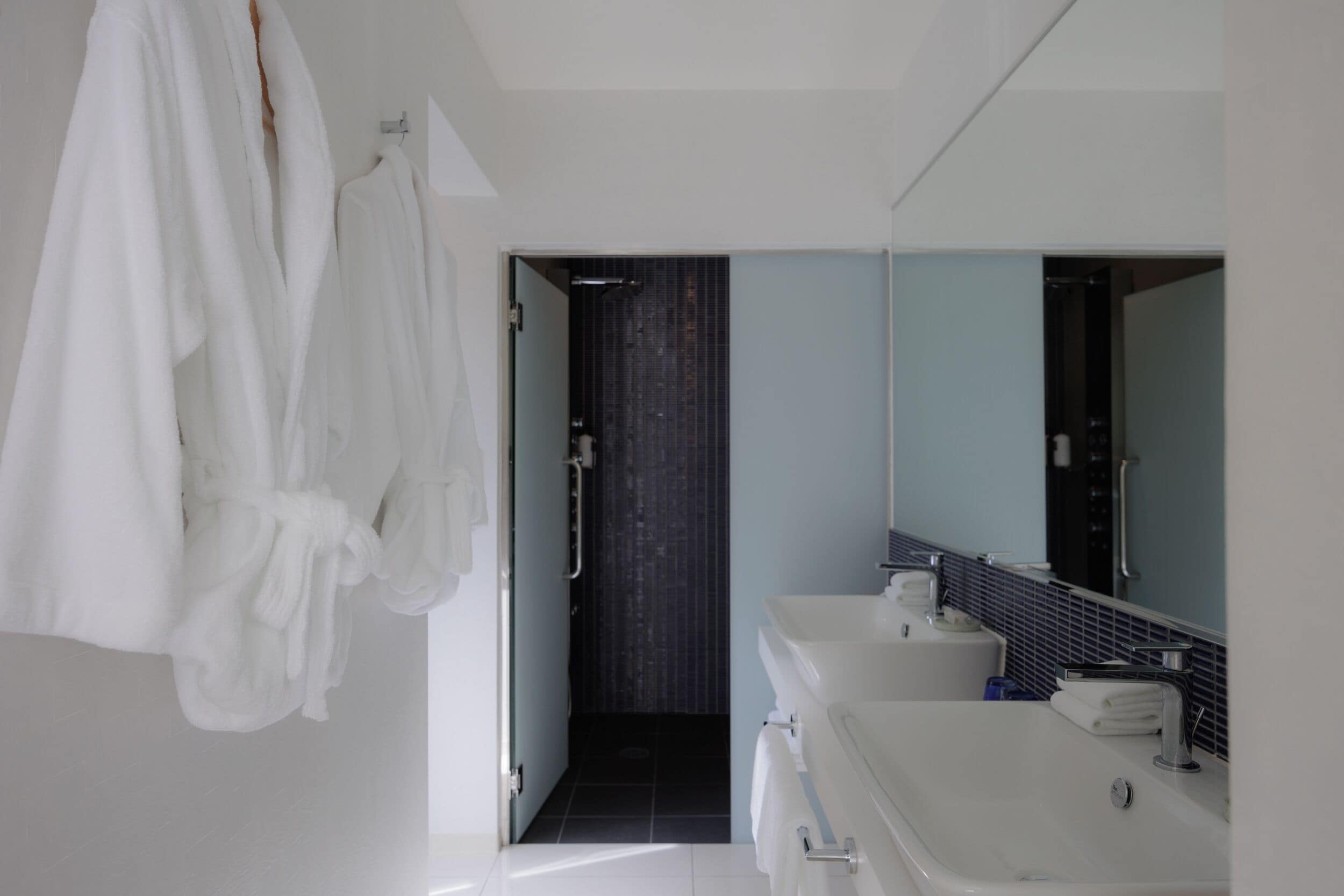A modern bathroom with a bathtub, a large mirror, and a white sink.