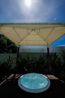 Un jacuzzi bajo un toldo, con cielo despejado arriba.