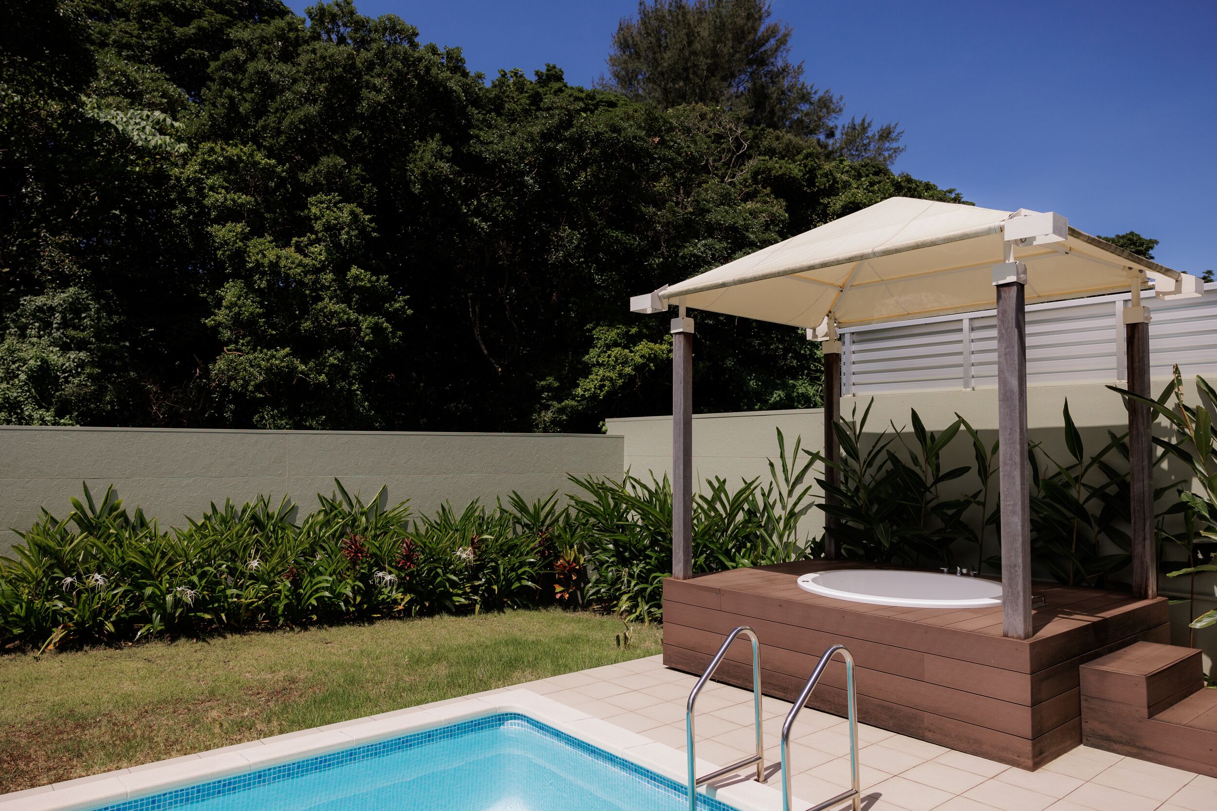 Una piscina con idromassaggio e zona relax coperta, immersa nel verde.