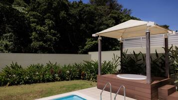 Una piscina con idromassaggio e zona relax coperta, immersa nel verde.