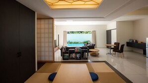 A modern living room with a view of a pool, a sofa, a coffee table, and a bookshelf. - YUMIHA OKINAWA (Onna)
