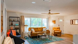 A living room with a sofa, armchair, coffee table, and a bookshelf. - Wow! Beachside Glam 3br wPool, Walk to Park, Beach (Satellite Beach)