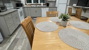 Eine moderne Küche mit grauen Schränken, einem Holztisch mit Platzsets und einem Fenster über der Spüle.