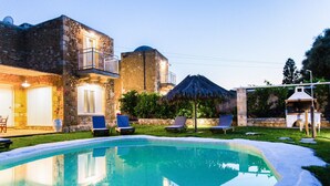 A swimming pool with lounge chairs, a stone building with a balcony, and a thatched umbrella. - Mysigt Villa - Next to Platanias, 2min from beach (GV2W+XM3 Platanias, Greece)