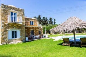 Ein Steinhaus mit Pool und einem Reetdachgebäude.