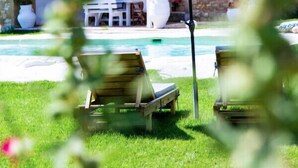 Ein Steinhaus mit Pool, Sitzgelegenheiten im Freien und einem weißen Sonnenschirm.