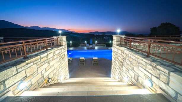 Una escalera de piedra que lleva a una piscina con vista al atardecer.