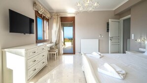 Un dormitorio con cama, cómoda, televisor y vista al mar.