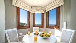 Un comedor con una mesa redonda, dos sillas, un cuenco de fruta y vasos de zumo de naranja.