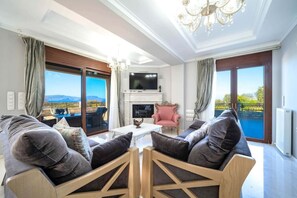 A spacious living room with a fireplace, a television, and a view of a pool and mountains.