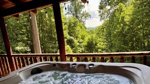 Un bain à remous avec une terrasse en bois et une vue sur une zone boisée.