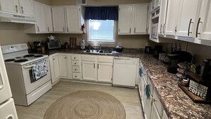 A kitchen with white cabinets, a stove, a microwave, and a sink. - Relax On The Coast (Foley)