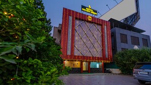 A hotel entrance with a large illuminated sign, a tiled pavement, and a parked car. - Itsy Hotels Golden Birds (Navi Mumbai)