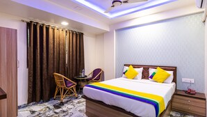 A hotel room with a bed, two chairs, a ceiling fan, and a marble floor. - Itsy Hotels Golden Birds (Navi Mumbai)