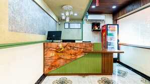 A reception area with a marble floor, a reception desk, a computer, and a Coca-Cola refrigerator. - Itsy Hotels Golden Birds (Navi Mumbai)