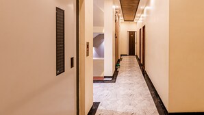 A hotel hallway with a patterned floor, a wooden ceiling, and doors numbered 102 and 103. - Itsy Hotels Golden Birds (Navi Mumbai)