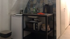 A compact kitchen with a stone backsplash, a small refrigerator, a microwave, and a sink. - TRAMONTANA apartment with whirlpool shower in the room (Taranto)
