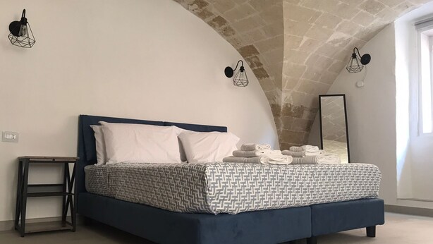 A bedroom with a bed, a nightstand, and a mirror. - TRAMONTANA apartment with whirlpool shower in the room (Taranto)
