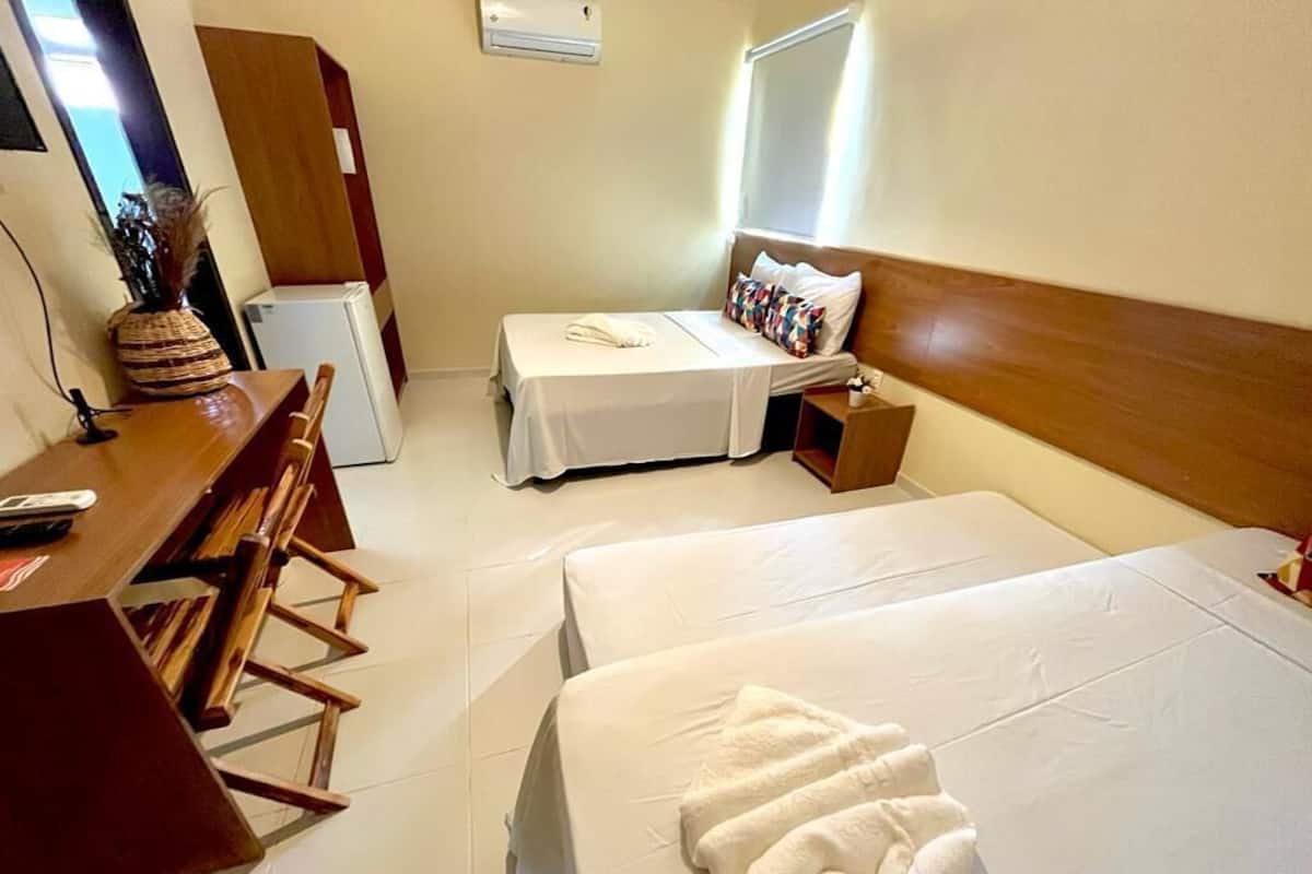 Une chambre d’hôtel avec deux lits, un bureau, une chaise, une petite table et un réfrigérateur.