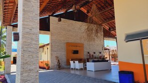 A modern outdoor lounge area with stone walls, a wooden ceiling, and a seating arrangement. - Hotel Arena Carneiros By AFT (Tamandaré)