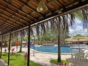 A covered outdoor area with a pool, seating, and a playground. - Hotel Arena Carneiros By AFT (Tamandaré)