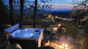 A hot tub in a natural setting with a view of a town in the background. - Villa "Il Diaccio" with a panoramic view of the Tuscan Maremma (Roccatederighi)