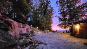 A stone pathway leading to a building with a tiled roof, surrounded by trees and a rocky landscape. - Villa "Il Diaccio" with a panoramic view of the Tuscan Maremma (Roccatederighi)