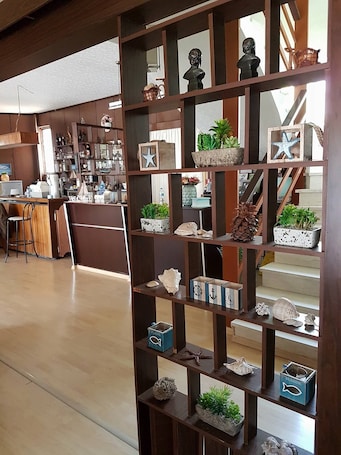 A wooden shelf with decorative items and plants, a staircase, and a kitchen area with bar stools.