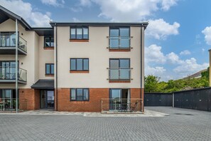 Ein mehrgeschossiges Wohngebäude mit Backsteinfassade, großen Fenstern und einem Balkon.