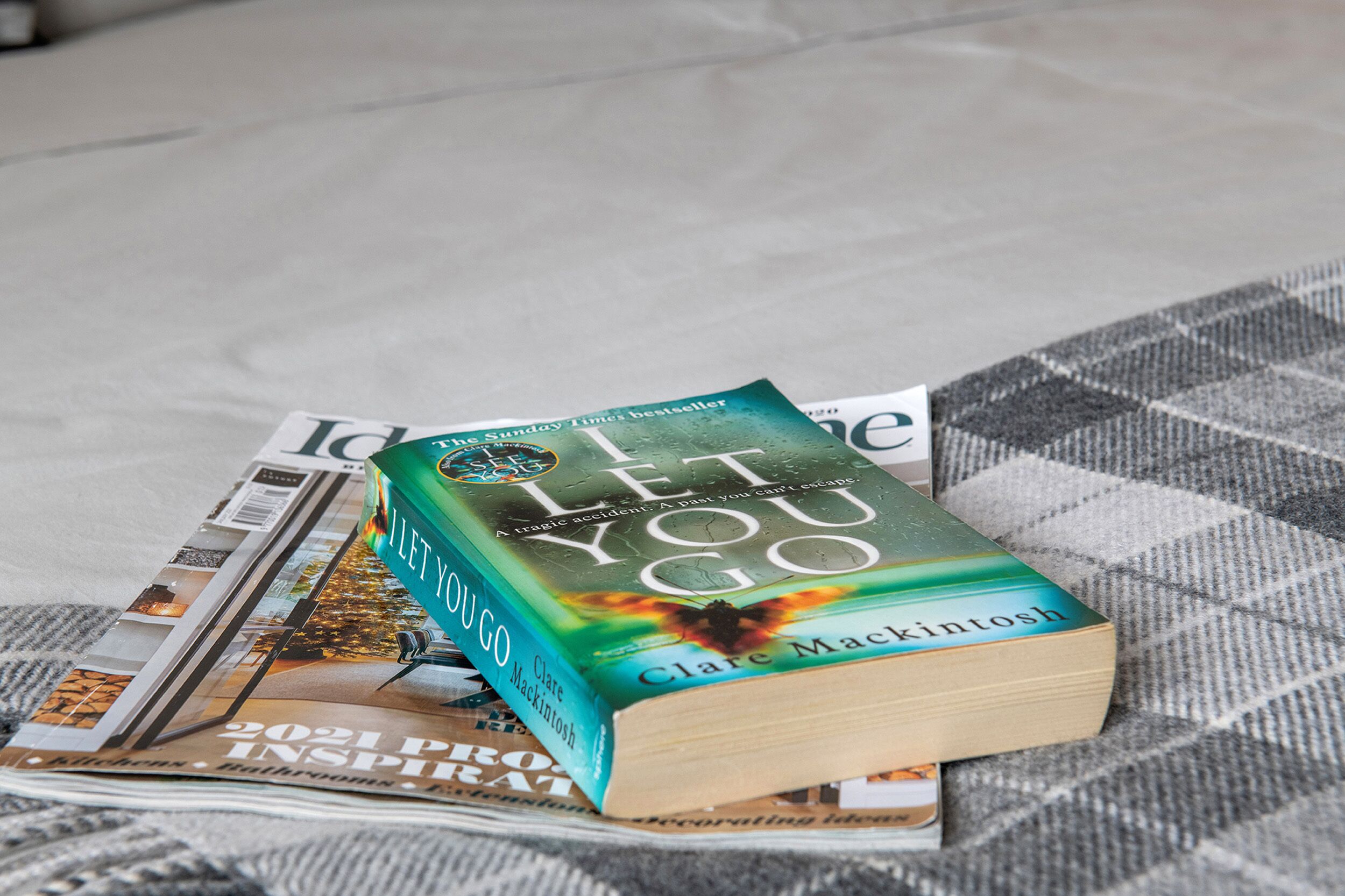 Ein Buch mit dem Titel 'I Let You Go' von Clare Mackintosh auf einer karierten Stoffoberfläche.