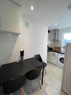 Enjoy meals in the kitchen with oven, stainless steel range hood, and washing machine, and dine at the table with two chairs.