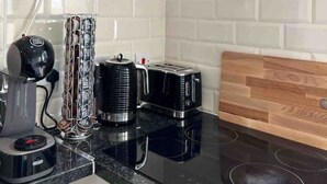 A modern kitchen with a black induction cooktop, a coffee machine, a toaster, and a glass hood over the stove.