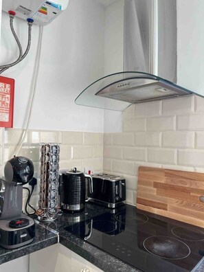 Kitchen features a sleek induction cooktop, coffee maker, and kettle, along with a wooden cutting board and white subway tiles.