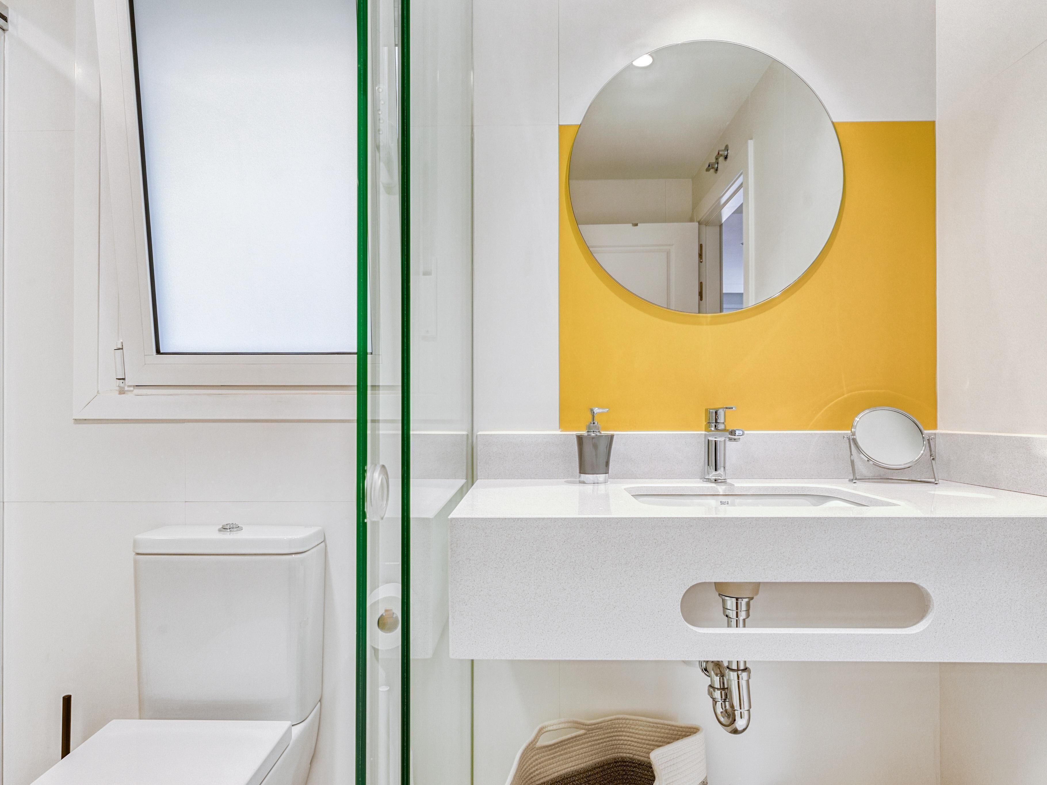 Een moderne badkamer met een wit wastafel, een spiegel en een toilet.