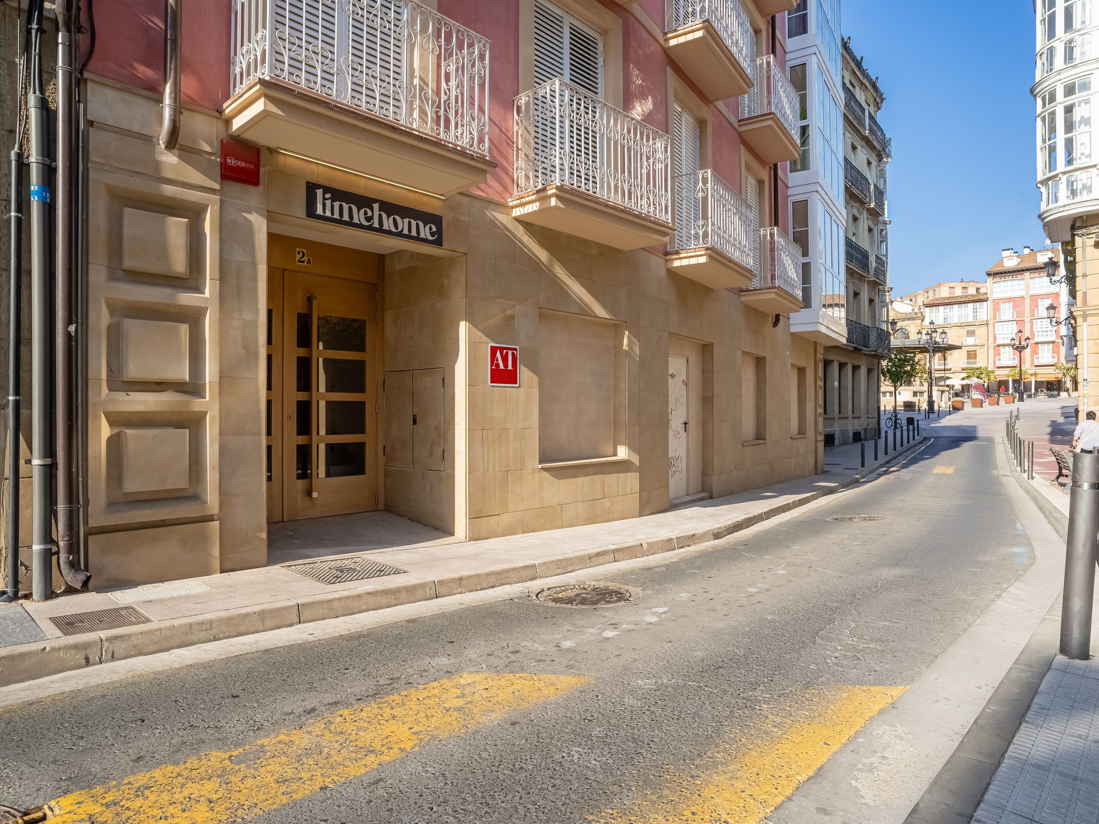 A building with a 'limehome' sign, a '2A' room number, and a red 'AT' sign on the door.