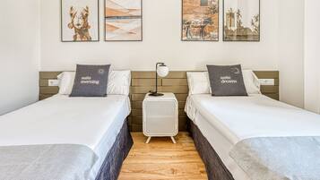 Habitación de hotel con dos camas, una mesita de noche y tres cuadros enmarcados en la pared.