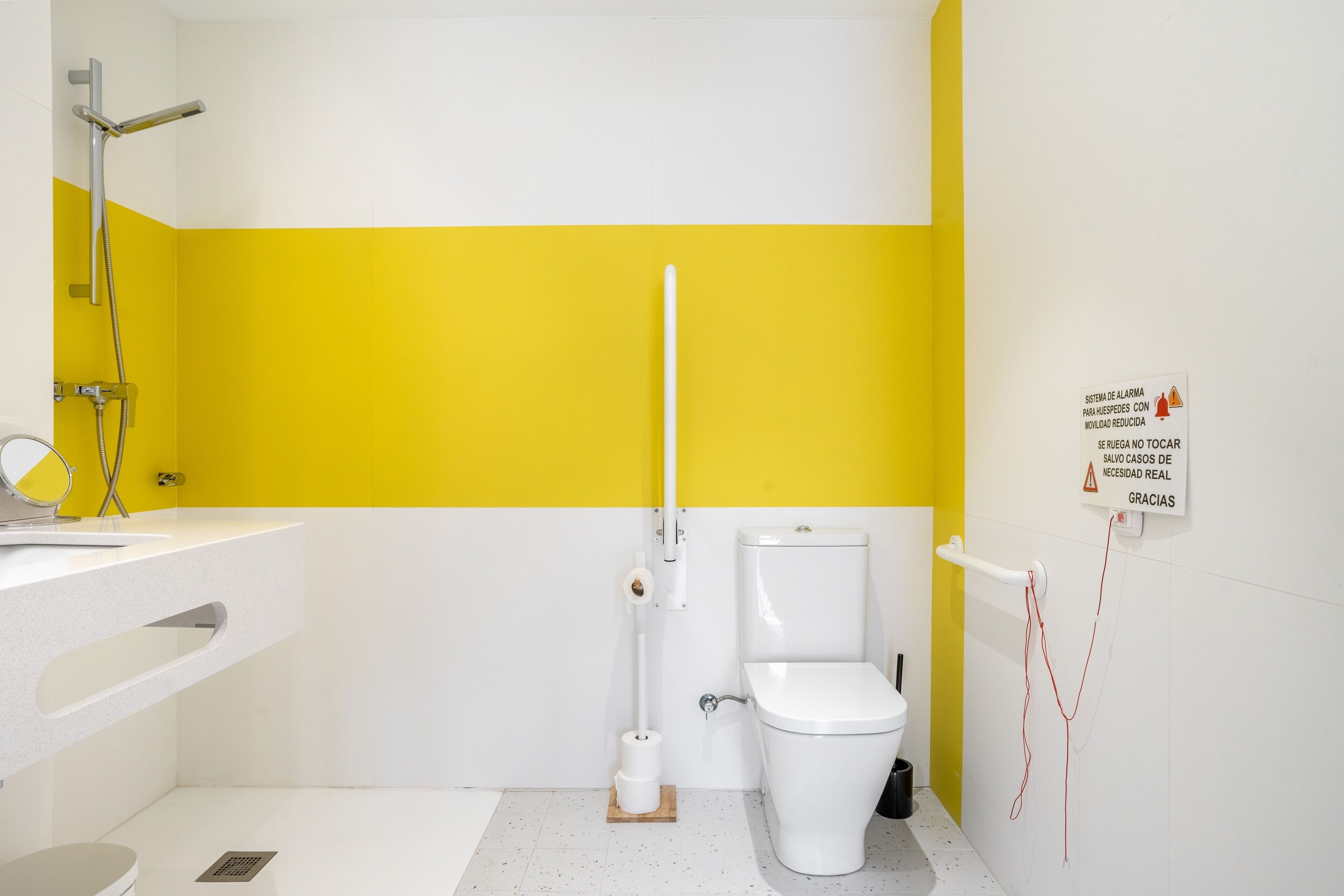 A bathroom with a white toilet, a yellow wall, and a white sink.
