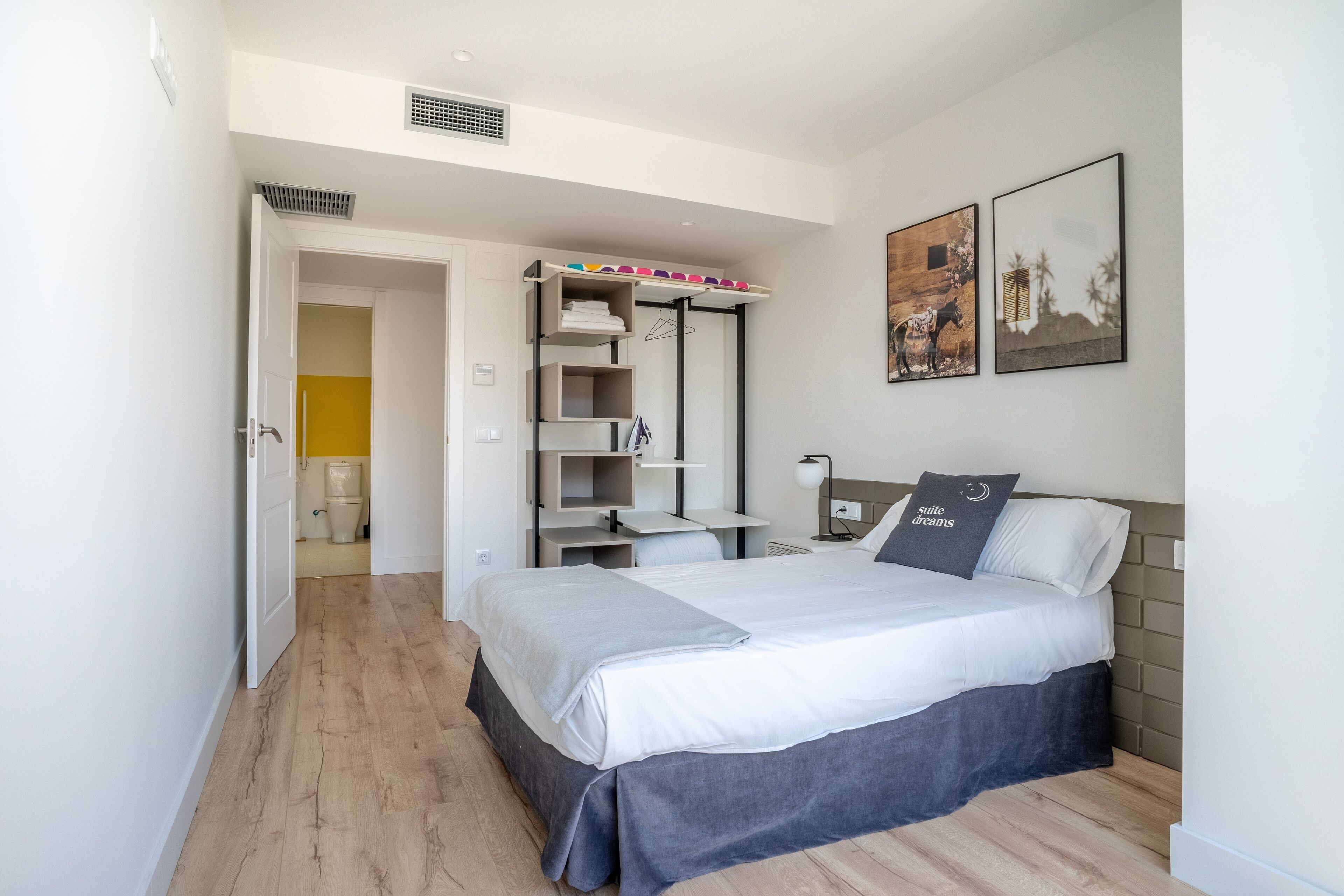 A modern bedroom with a bed, a built-in wardrobe, a desk, and a nightstand.