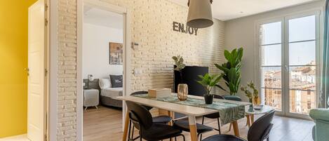 Ein modernes Wohnzimmer mit Essbereich, einer Couch und einem großen Fenster mit Blick auf die Stadt.