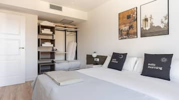 Une chambre d’hôtel moderne avec un lit bien fait, un placard intégré avec espace pour suspendre les vêtements, et deux tableaux encadrés accrochés au mur.