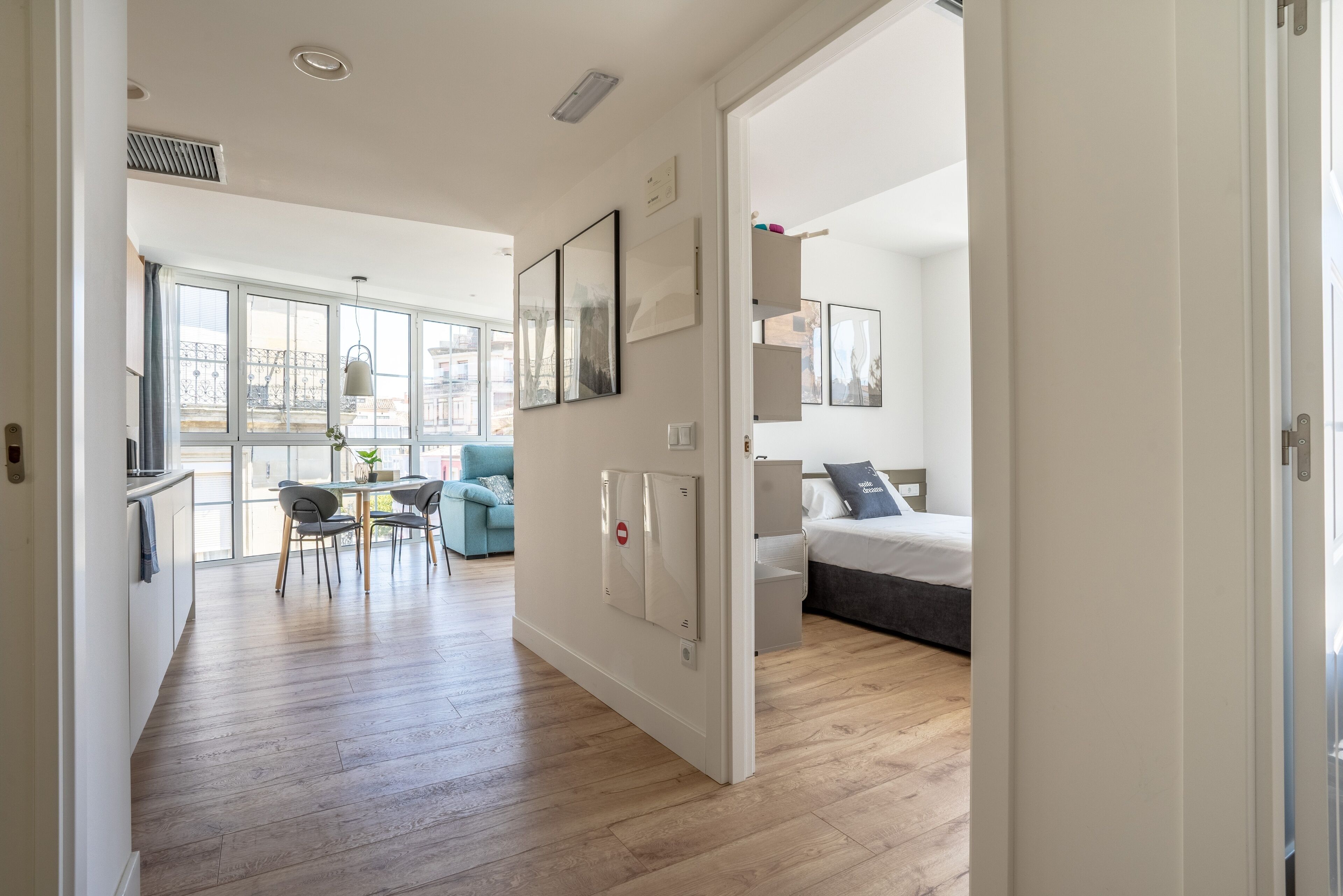 Un apartamento moderno con comedor, sala de estar con sofá y cama, y un ventanal que proporciona luz natural.