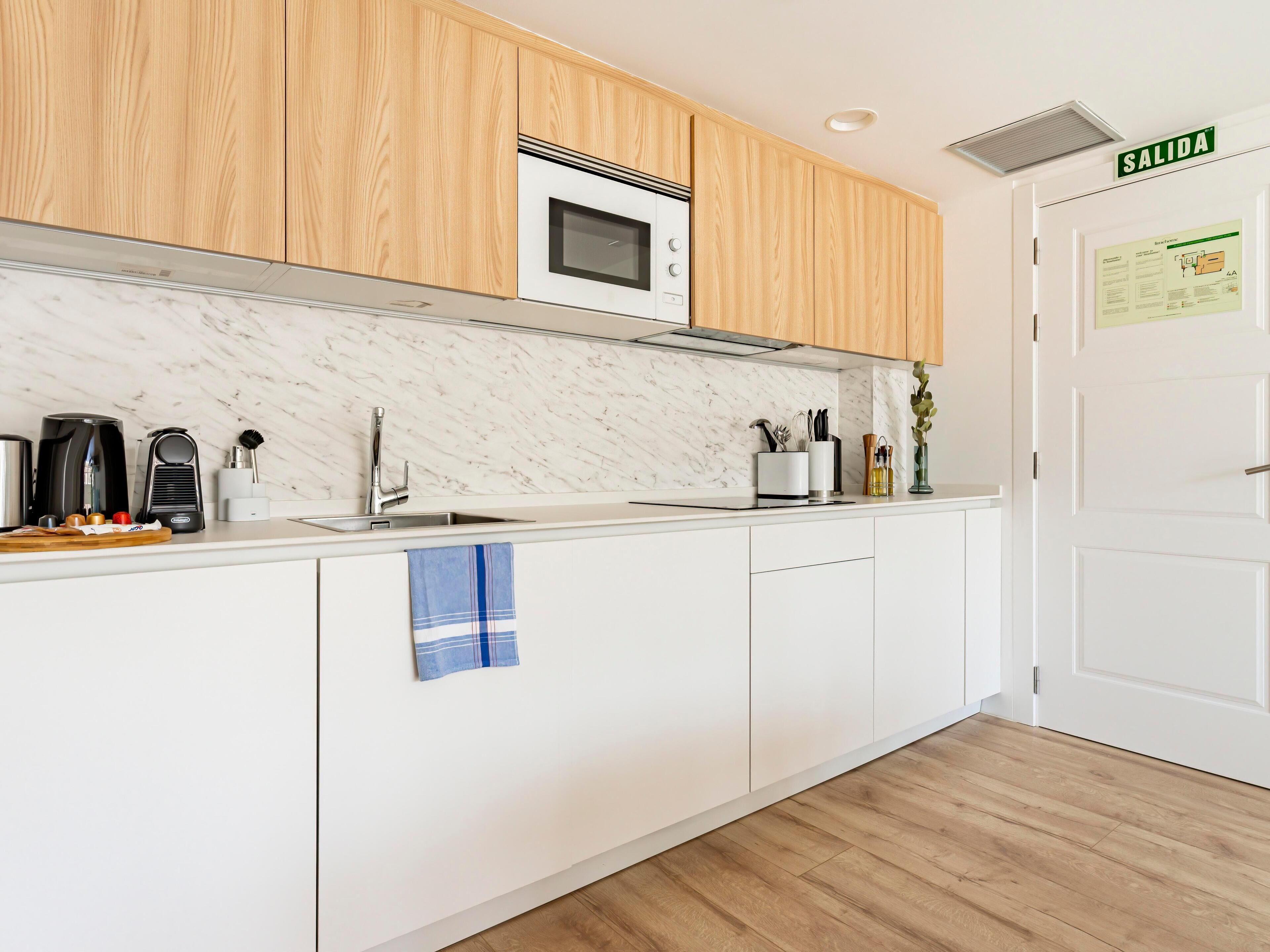 A modern kitchen with wooden cabinets, a microwave, a sink, and a coffee maker.