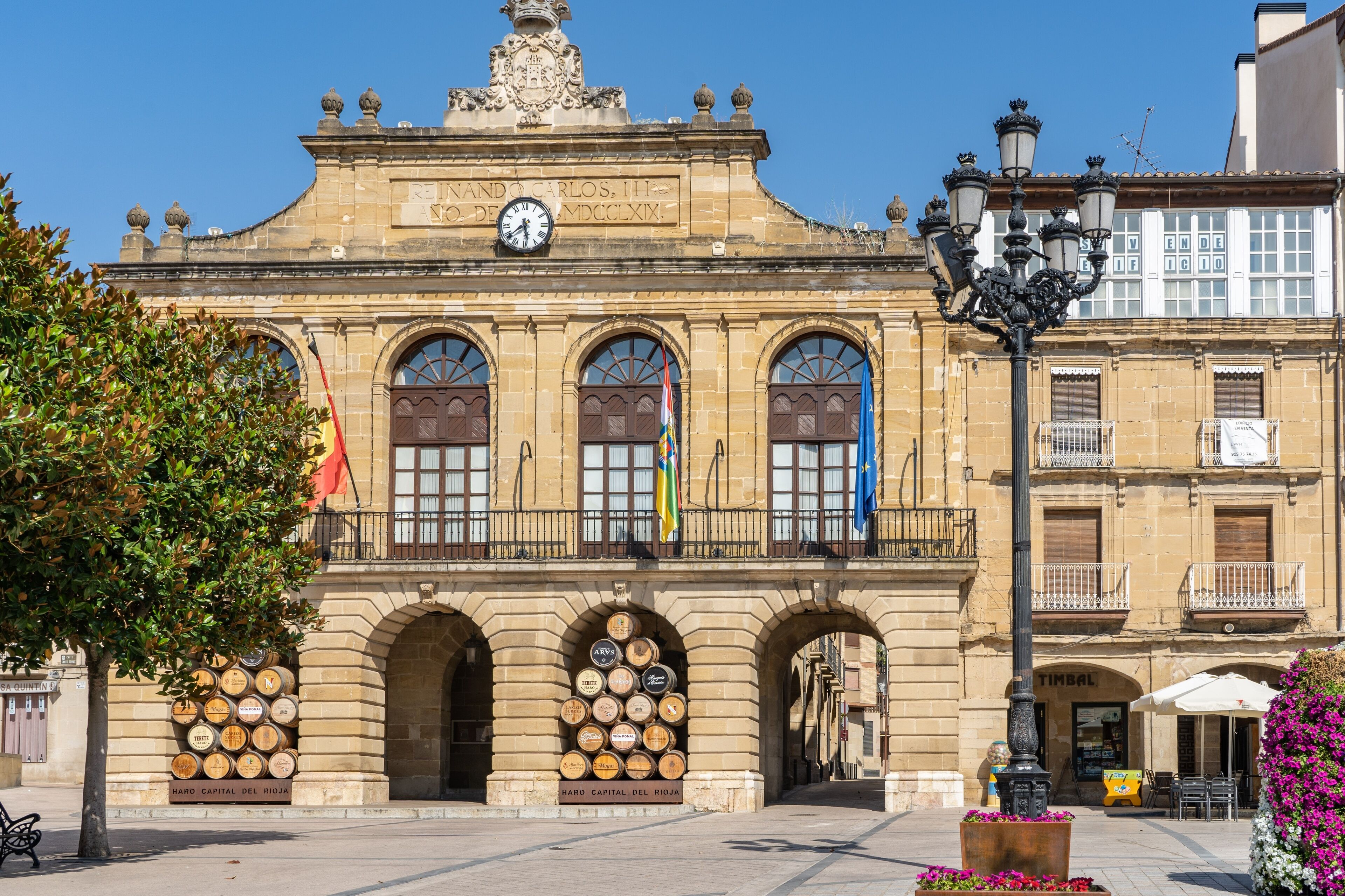 A historic building with arched windows and a clock, featuring a sign that reads "HARD CAPITAL DEL RIOJA".