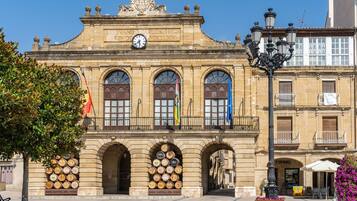 A historic building with arched windows and a clock, featuring a sign that reads "HARD CAPITAL DEL RIOJA".