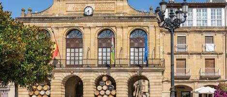 A historic building with arched windows and a clock, featuring a sign that reads "HARD CAPITAL DEL RIOJA".