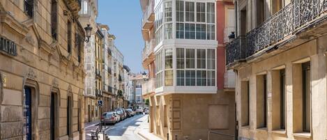A narrow street lined with historic buildings, featuring balconies and large windows.